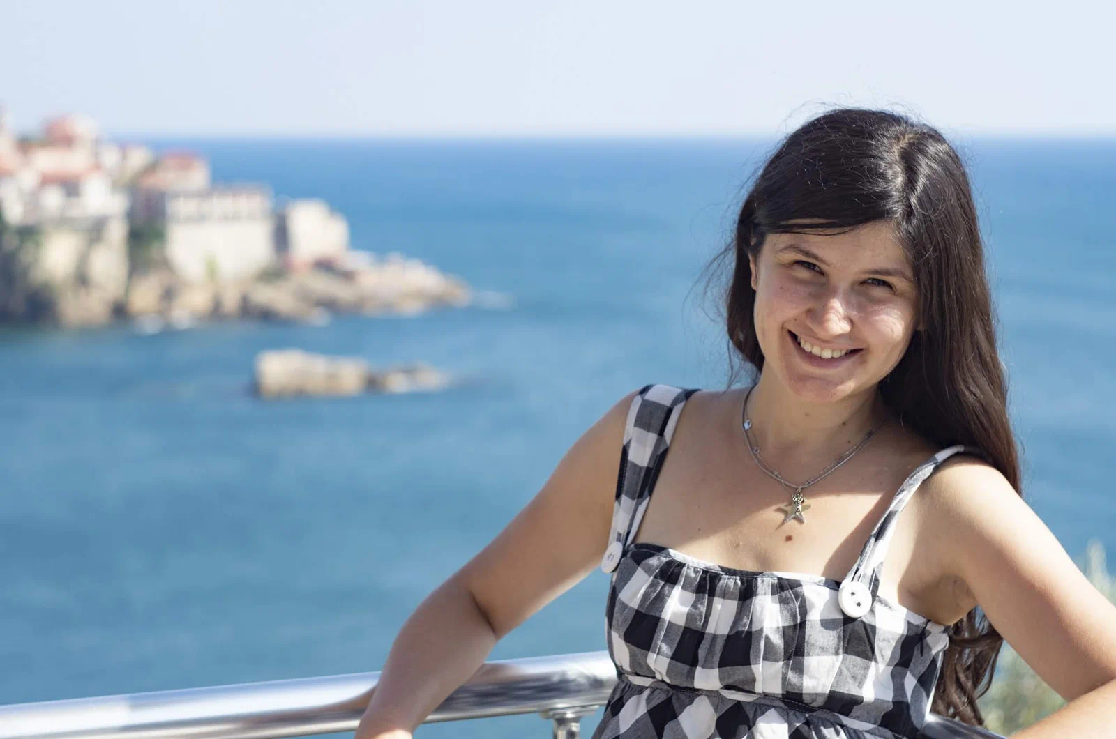 Travel blogger Ket smiling with Ulcinj old town and the Adriatic Sea in the background, Montenegro