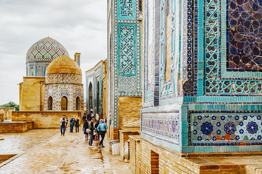 Shah-i-Zinda complex in Samarkand with tiled mausoleums and domes and visitors