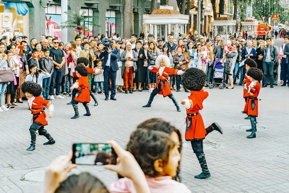 Traditional dancers performing in Tashkent street with crowd watching and taking photos