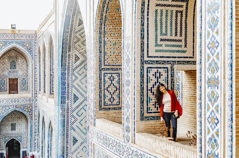 Woman standing in tiled corridor of Ulugh Beg Madrasa at Registan in Samarkand